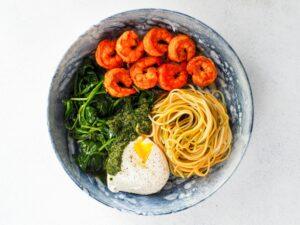 A vibrant top view of a shrimp, spinach, egg, and noodle pasta bowl, perfect for a healthy meal.