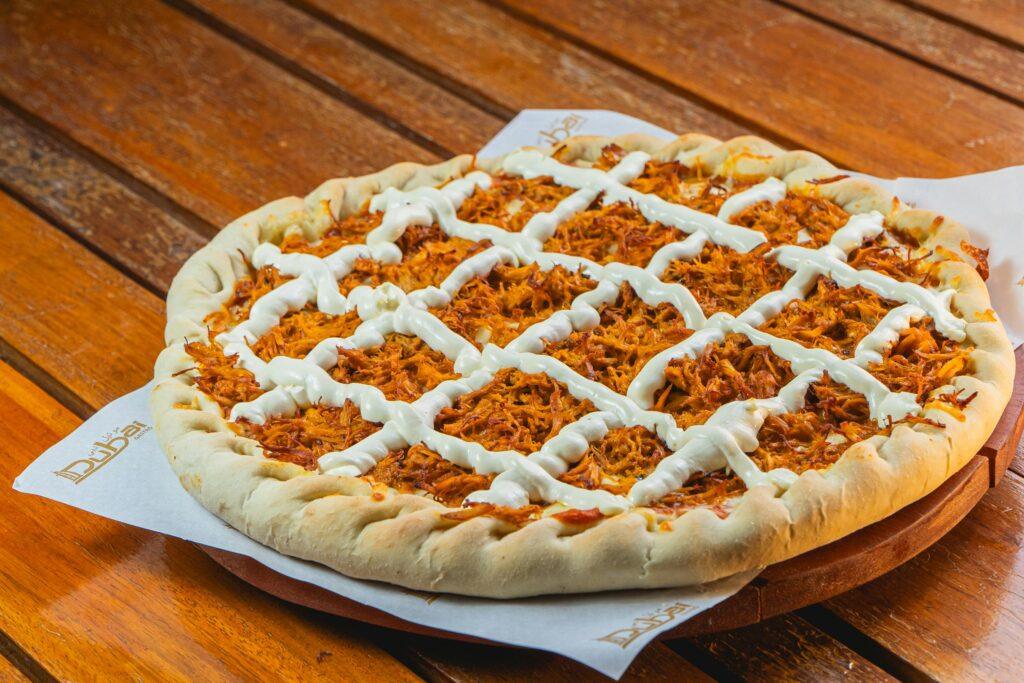 Savory barbecue chicken pizza topped with creamy sauce on a rustic wooden table.