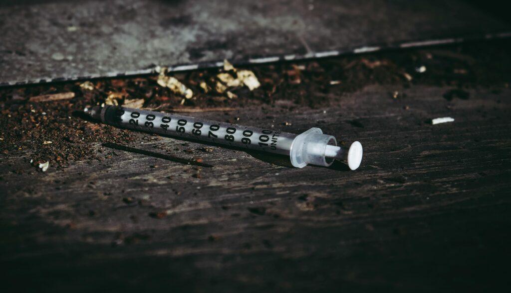 Close-up of a discarded syringe on a rough surface highlighting addiction issues.