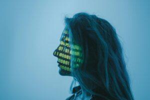 Silhouette of a woman with binary code projected on her face in a digital concept setting.